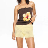 Woman wearing a brown strapless top with a floral design and yellow shorts